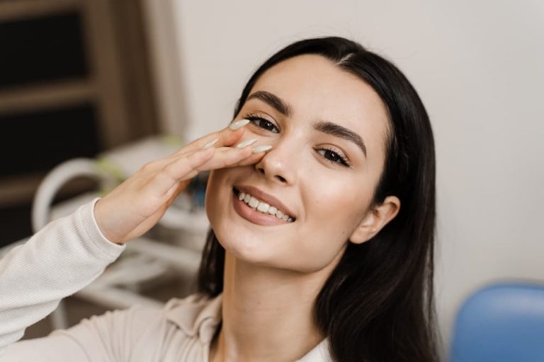 Mulher sorrindo e tocando o nariz, destacando a satisfação e a confiança após uma rinosseptoplastia, evidenciando os resultados positivos do procedimento.